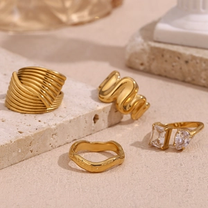 Detailed view of four 18K gold plated stainless steel rings with zircon and wavy textures