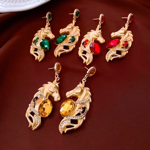 Détail de boucles d'oreilles tête de cheval avec cristaux vert rouge et ambre brillants