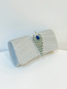 Detailed view of silver evening clutch with peacock clasp and blue rhinestones
