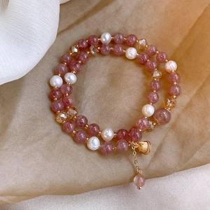 Détail du bracelet en quartz fraise et perles avec pendentif coquillage sur fond de soie