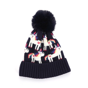 Dettaglio del berretto in maglia blu scuro con motivi a unicorno e un grande pompon
