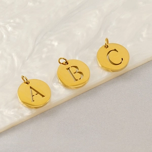 Macro view of gold stainless steel hollow alphabet charms A B C on a textured shell