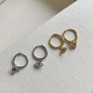 Detailed view of silver and gold S925 sterling silver evil eye earrings with blue crystals