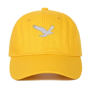 Détail d'une casquette en coton jaune avec broderie d'aigle argentée et œillets d'aération