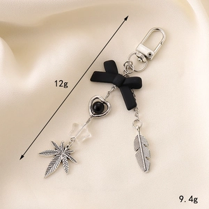 Bow cross keychain with heart and star pendants on beige fabric, weighing 12g