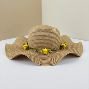Détail d'un chapeau de paille à larges bords avec abeilles décoratives et fleurs