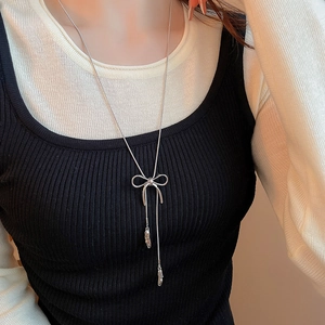 Detail shot of a silver bow necklace with long tassels and irregular metal pendants