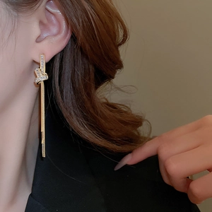 Detail of long tassel earrings with gold knot design and shimmering zircon stones