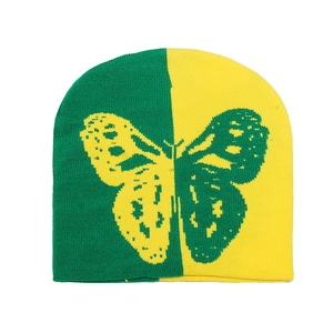 Détail du bonnet en tricot bicolore vert et jaune orné d'un grand motif papillon