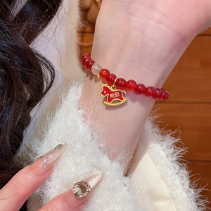Détail du bracelet en perles d'agate rouge avec breloque cheval doré et gravure de chance
