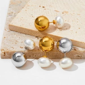 Orecchini minimalisti con sfera d'acciaio e perla su display in pietra di travertino beige