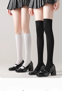 Détail de chaussettes montantes côtelées noires et blanches avec chaussures Mary Jane