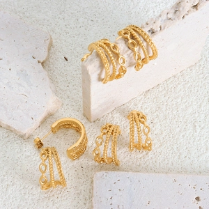 Three-layer C-shaped 18K gold plated titanium steel earrings on a light textured stone