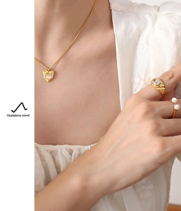 Detail shot of heart opal pendant necklace and gold rings worn by a model