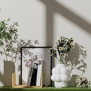 Jarrón de cerámica blanca con forma de nube y margaritas en una decoración minimalista
