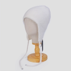 Close-up of white angora fur trapper hat with long earflaps and knit texture