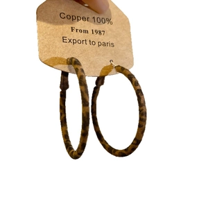 Vintage leopard print round hoop earrings in copper material held for display