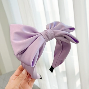 Close-up of a purple satin bow headband with a glossy finish for elegant hair styling
