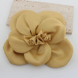 Detailed top view of a large yellow fabric camellia flower with silky texture and pleats