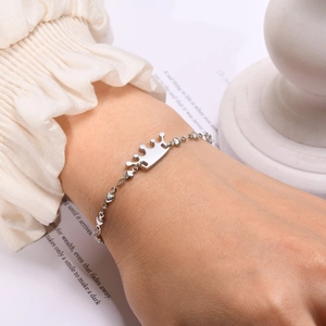 Detail of silver crown pendant on a heart-shaped link chain bracelet for women