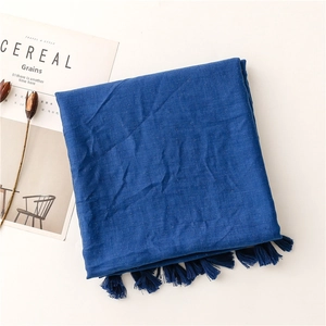 Detail of dark blue linen scarf with decorative tassels and gold shimmer accents