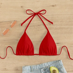 Close-up of red halter bikini top with adjustable ties on a light wooden background