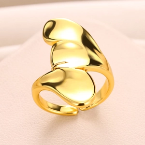 Close-up of a polished gold-plated abstract butterfly ring on a soft pink leather background