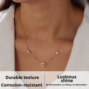 Close-up of gold chain necklace featuring light blue heart stones and a pavé heart pendant