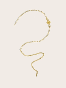 Detail of golden metal chain belt with pearl accents in an elegant S-shaped layout