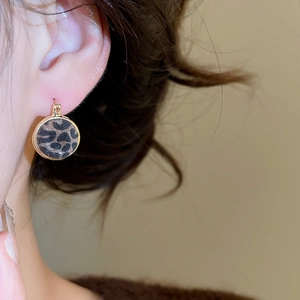 Close-up of vintage leopard print hoop earrings with gold metal accents on a model