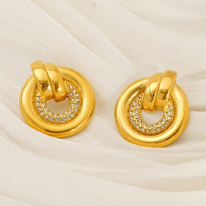 Détail de boucles d'oreilles créoles dorées avec design circulaire et cristaux pavés étincelants