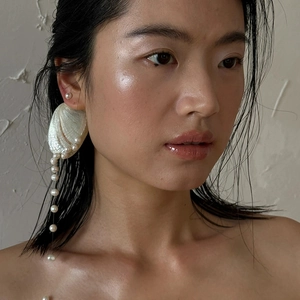 Artistic silver needle shell and freshwater pearl fringe earrings worn by a model