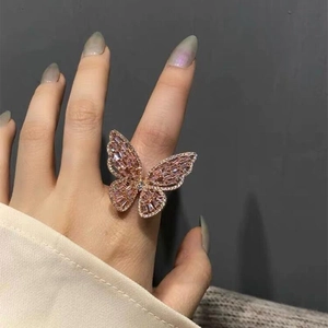 Close-up of a large rose gold butterfly ring with pink zircon crystals on a finger