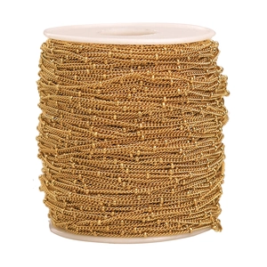 Macro view of golden stainless steel spacer bead chain on a white plastic reel for DIY jewelry