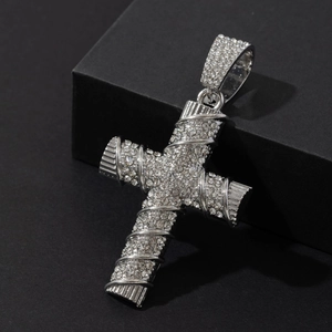 Macro shot of silver iced out cross pendant with sparkling crystals and spiral textures