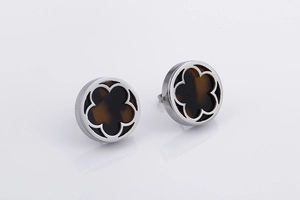 Detailed view of round silver earrings with clover design on a white reflective surface