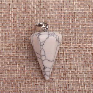 Macro shot of white turquoise cone pendant with black veins on rustic burlap fabric