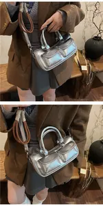 Detailed view of a metallic silver saddle bag with dual front pockets and silver hardware