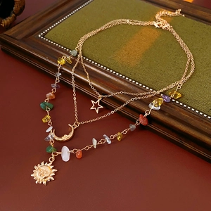 Detail of layered gold necklaces with sun, moon, star pendants and colorful stones