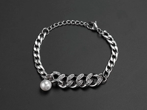 Detail view of silver Cuban link bracelet with sparkling rhinestones and a white pearl charm