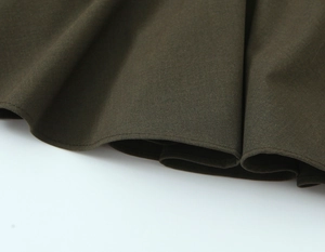 Gros plan détaillé de l'ourlet en tissu vert olive avec coutures fines et texture