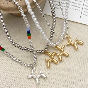 Dettaglio di collane con ciondolo a cane palloncino, perline metalliche e ciondoli colorati