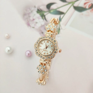 Close-up of a floral gold watch with rhinestones and a quartz dial on a pink background
