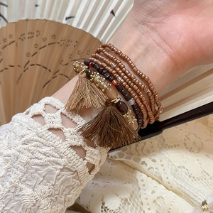 Detail of layered Bohemian beaded bracelet set with brown tassels and gold crystal accents