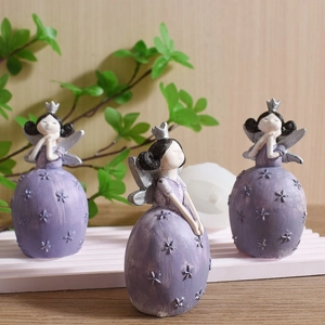 Three purple fairy figurines with silver wings on a decorative display stand