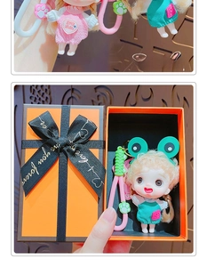 Detailed view of a cute cartoon doll keychain with green dress and orange gift packaging
