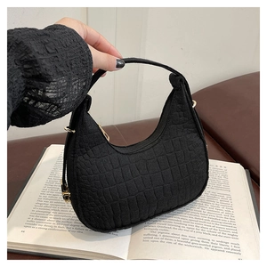 Detail of black crocodile texture felt handbag with gold hardware and shoulder strap