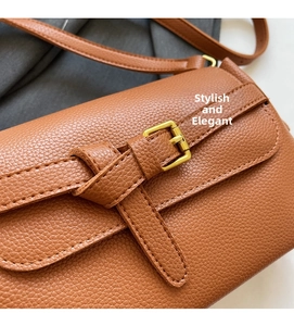Close-up of brown pebbled leather crossbody bag with golden buckle and fine stitching