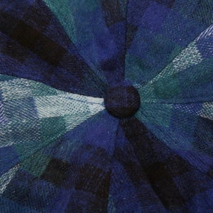 Close-up of blue and green plaid fabric texture and top button on the beret hat
