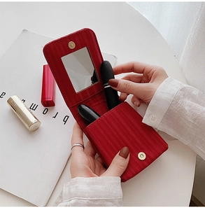 Detail of red striped leather lipstick case featuring a built-in mirror and magnetic closure